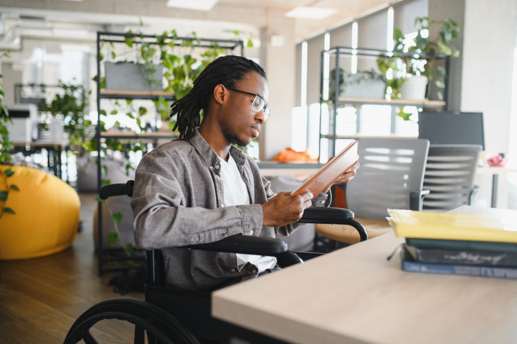 Focused student with disability using tablet in modern office